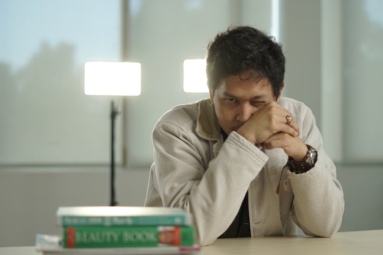 Baskara Putra atau Hindia dengan kedua tangan terangkat mengenakan jaket putih